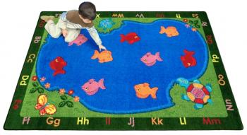A student sits on a rectangular shaped kids floor rug with fish.