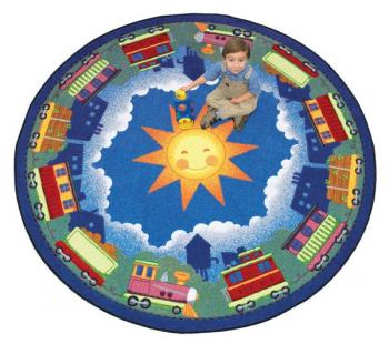 A boy sits on a circle shaped "In Training" train nursery rug.