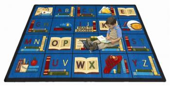 A student sitting on a rectangle shaped alphabet daycare rug.