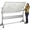 A teacher stands beside a large double sided dry erase board.